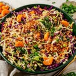 a big bowl of mandarin orange chicken salad topped with fresh cilantro and green onions.