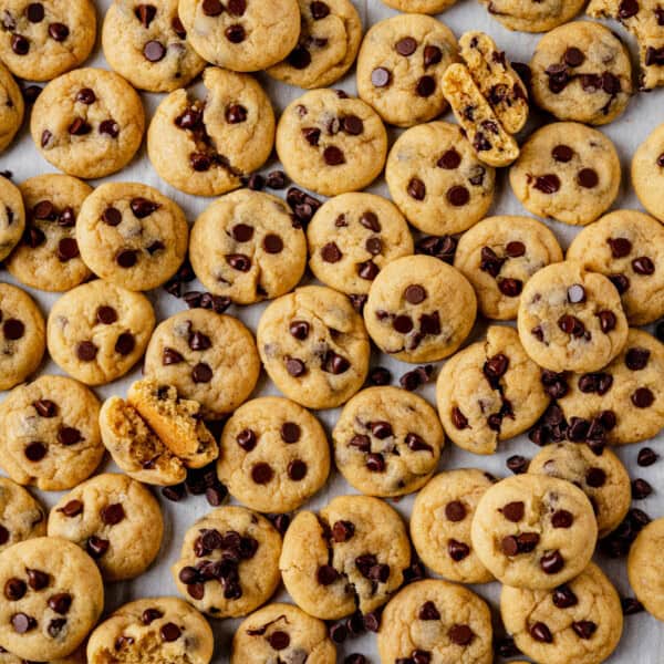 a sheet pan full of mini chocolate chip cookies with a few broken in half to see the soft centers.