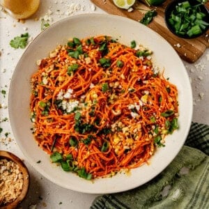 a serving bowl of carrot ginger salad with finely shredded carrots and topped with cilantro and green onions.