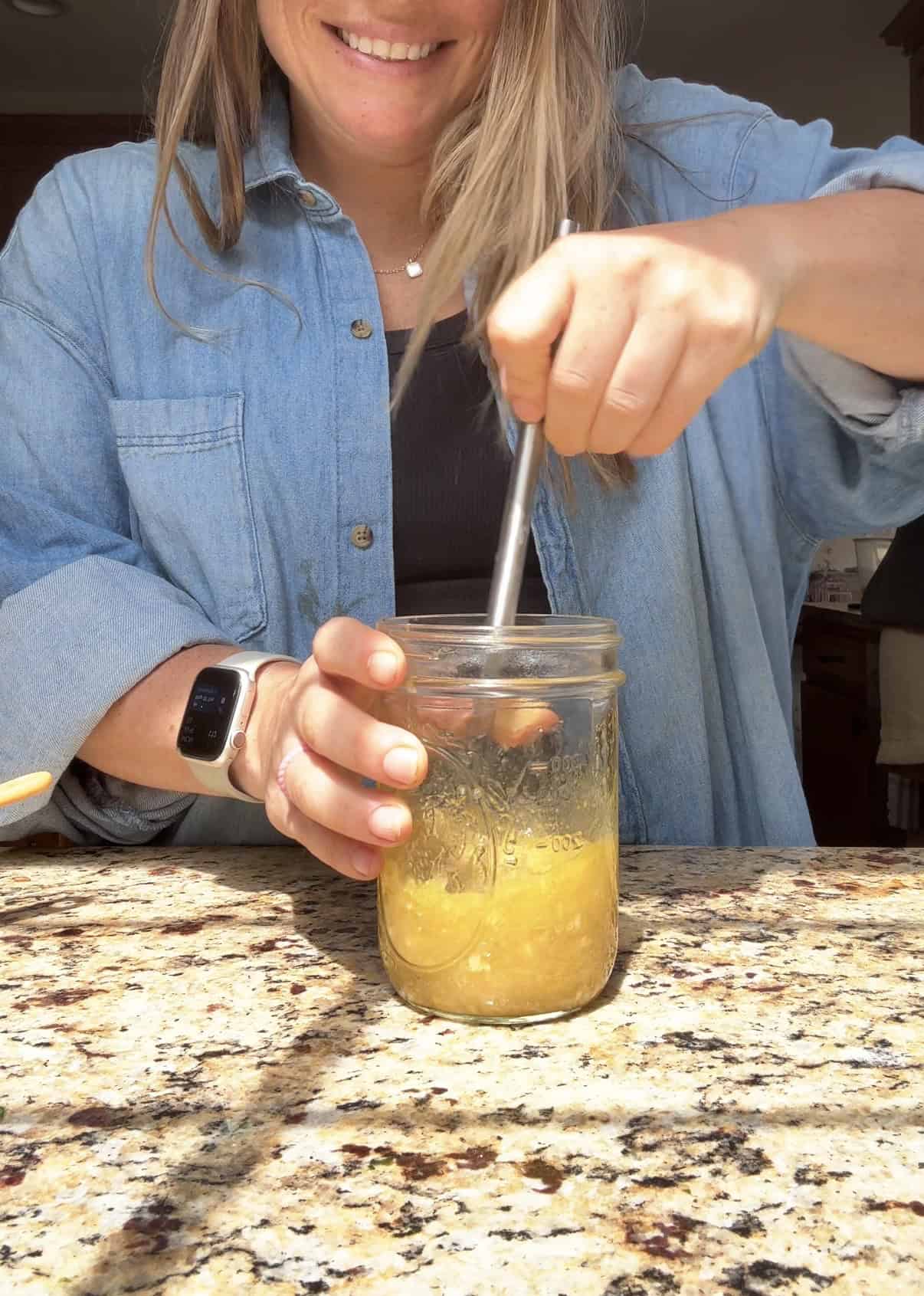 whisking ginger carrot salad dressing in a mason jar on the counter.