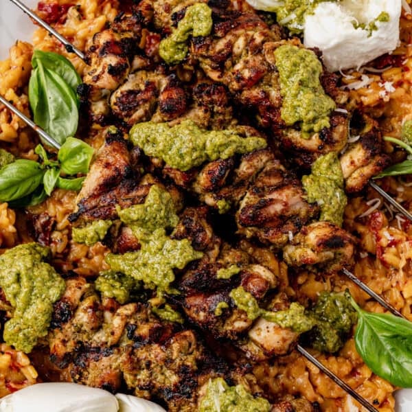 Pesto grilled chicken skewers topped with pesto sauce, served over a bed of tomato orzo with fresh basil leaves and dollops of creamy white burrata.