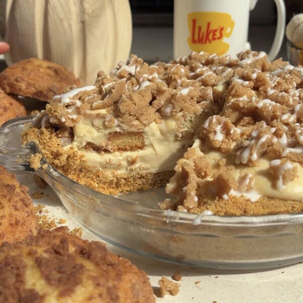 A crumb-topped pie with a creamy filling and graham cracker crust, with a slice removed, next to a mug labeled Lukes.