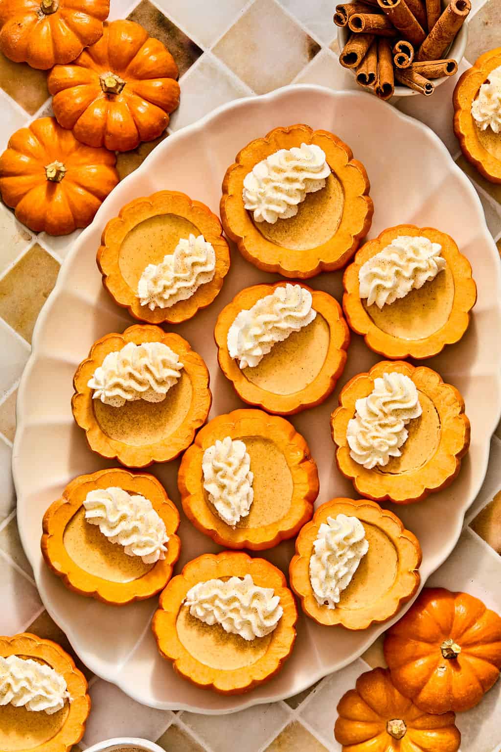A platter of pumpkin possets inside inside hollowed-out mini pumpkins, topped with swirls of whipped cream.